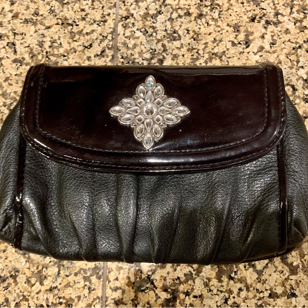 LN BRIGHTON CLUTCH W/CRYSTAL MEDALLION. PEBBLE LEATHER W/PATENT LEATHER TRIM.